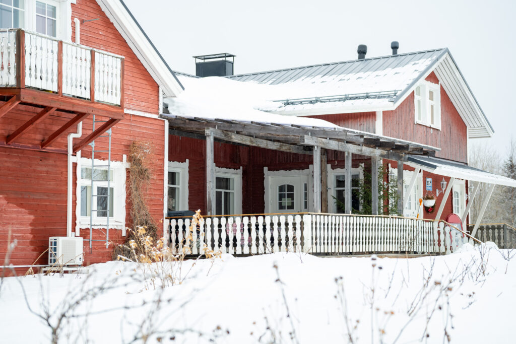 Kuvassa punavalkoinen Heikkilän Pirtti kuvattuna ulkoapäin. Luminen talvimaisema.