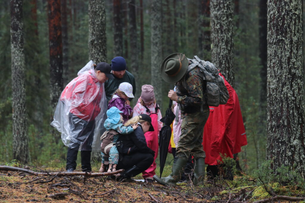 Neljä lasta ja neljä aikuista tutkivat metsässä pulmatehtävää.