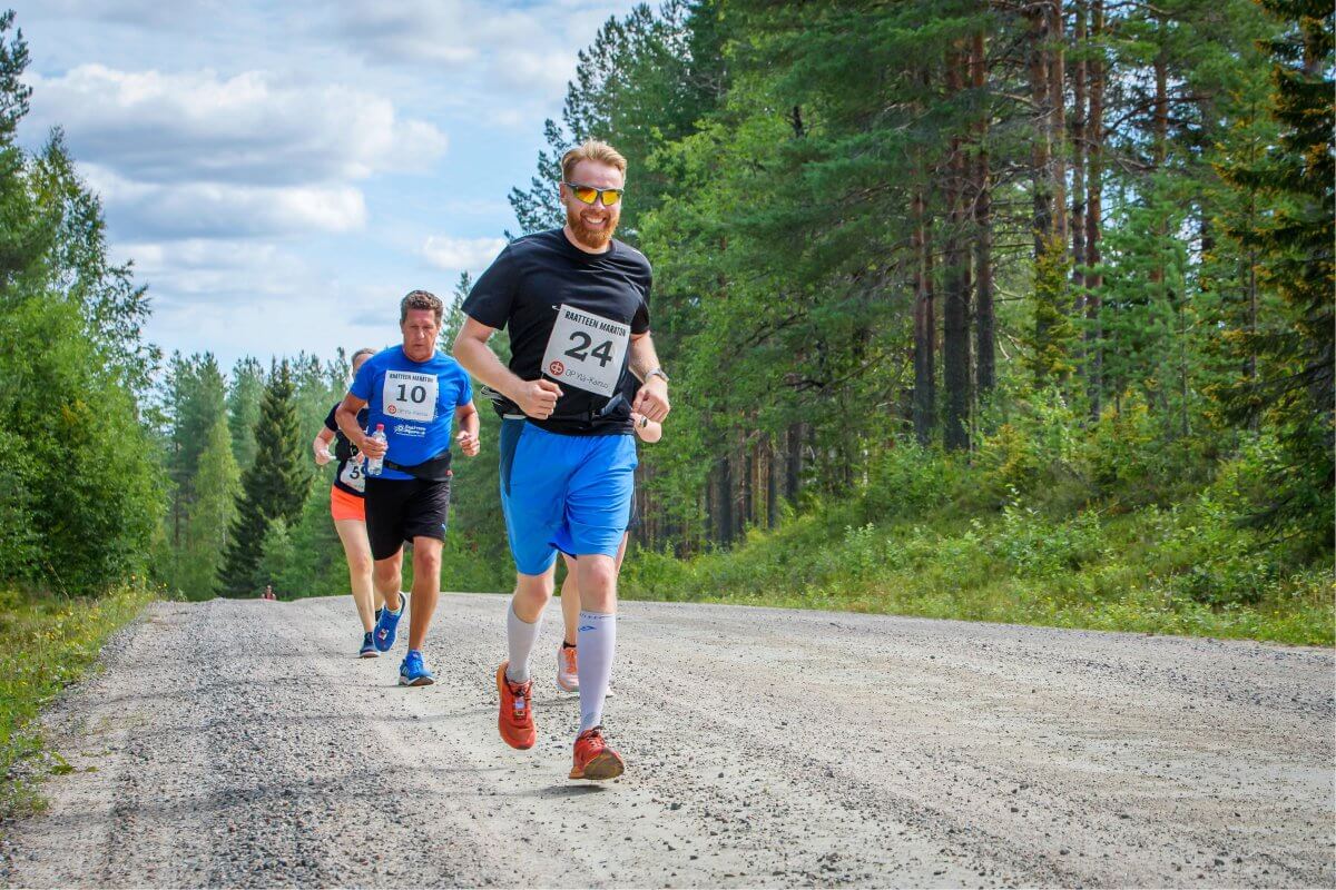 Ihmiset juoksevat hiekkatiellä.